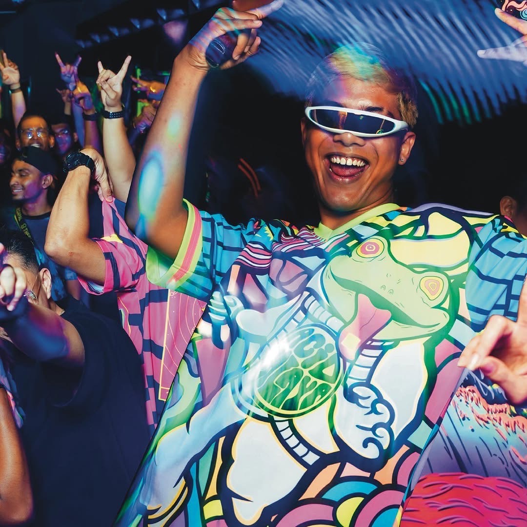 Man in LED glasses and a psychedelic Acid Malaya shirt dancing