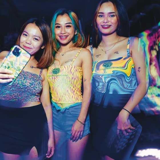 Three friends taking a selfie, two in matching psychedelic tops