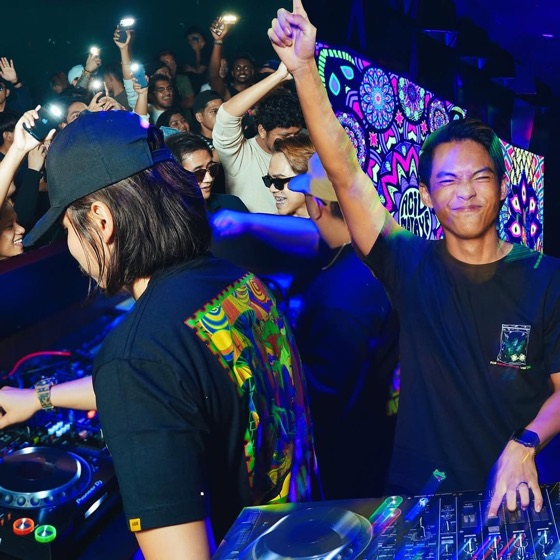 DJ at the decks with the crowd cheering behind
